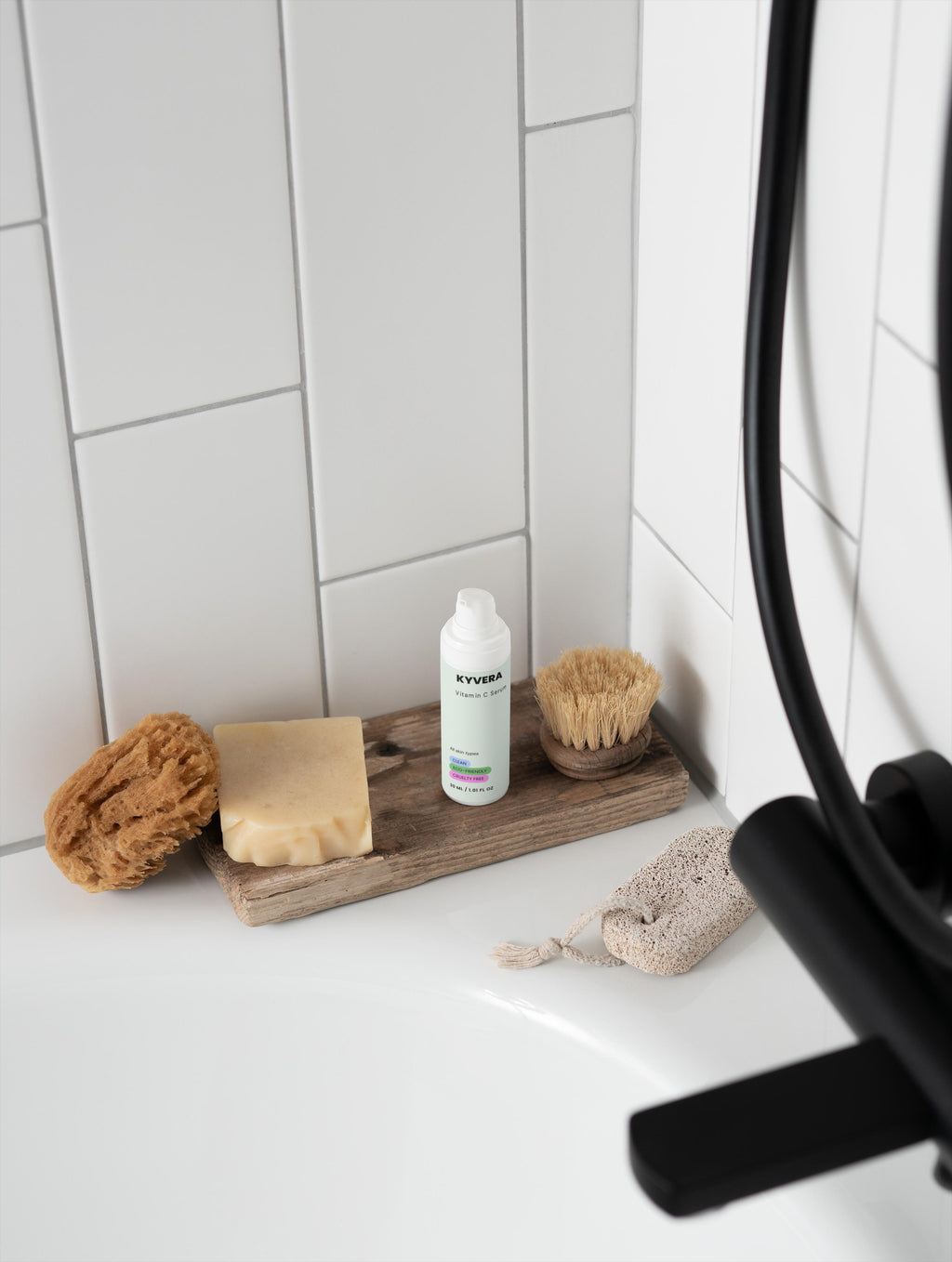 Vitamin C Serum placed beside natural sponges and a soap bar on a wooden tray in a minimalistic bathroom.