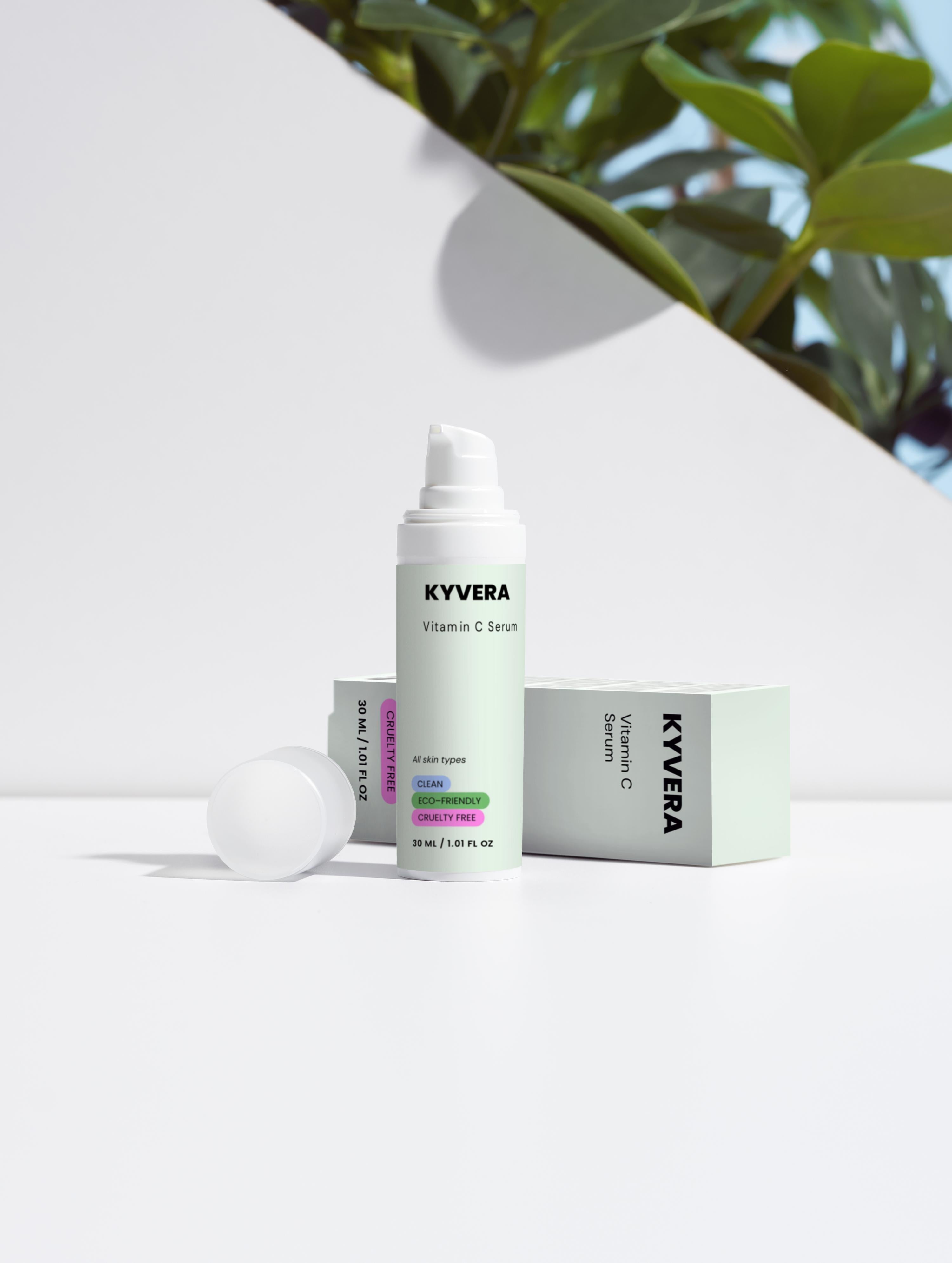 KYVERA Vitamin C Serum bottle next to product box on a bright surface with greenery in the background.