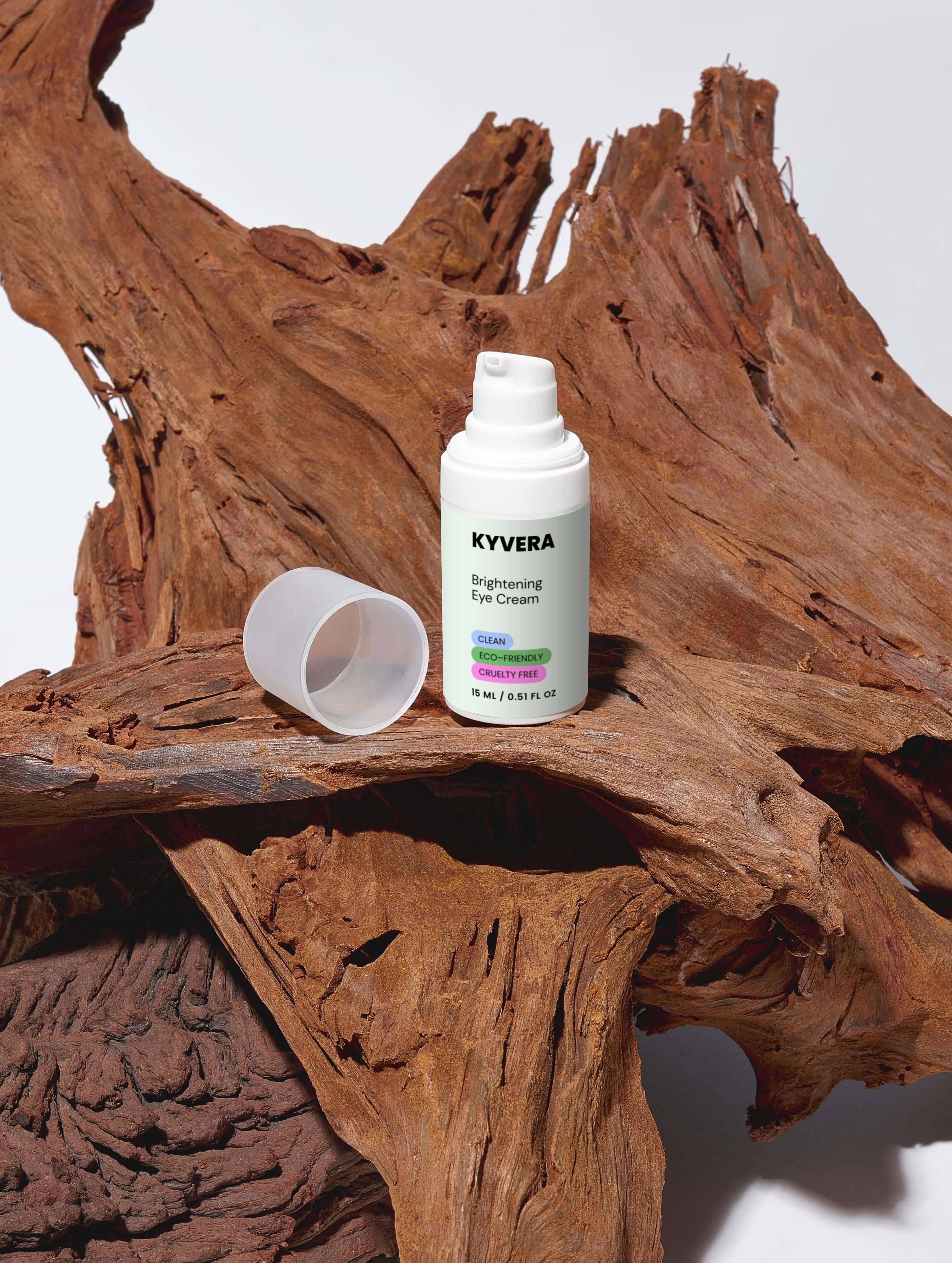 KYVERA Brightening Eye Cream bottle on natural wood background, showcasing skincare for puffiness and dark circles.